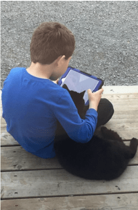 Boy with his black cat watching his Ipad
